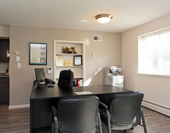 an office with a desk and chairs and a window