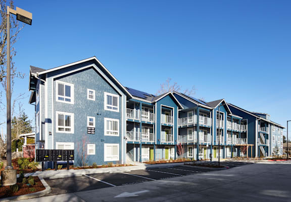 A large blue building with a parking lot in front.