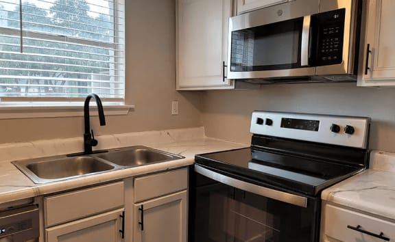 a kitchen with a sink and a stove and a microwave at Ivy Plains at Brooks Apartments, San Antonio