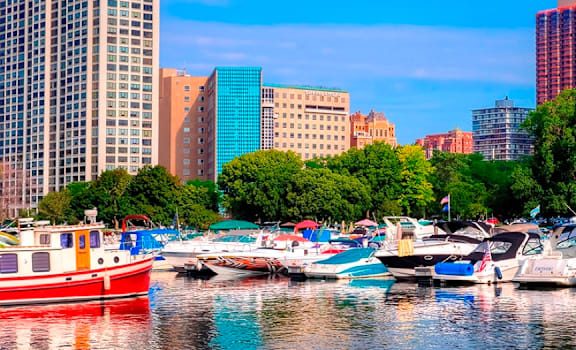 A red boat is docked in a marina with other colorful boats.