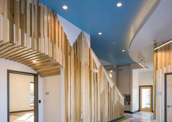 A hallway with a blue ceiling and a wooden staircase.