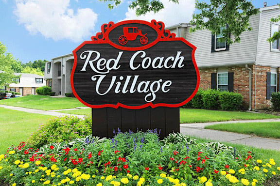 Red Coach Village entrance sign with flower beds in Springfield, OH