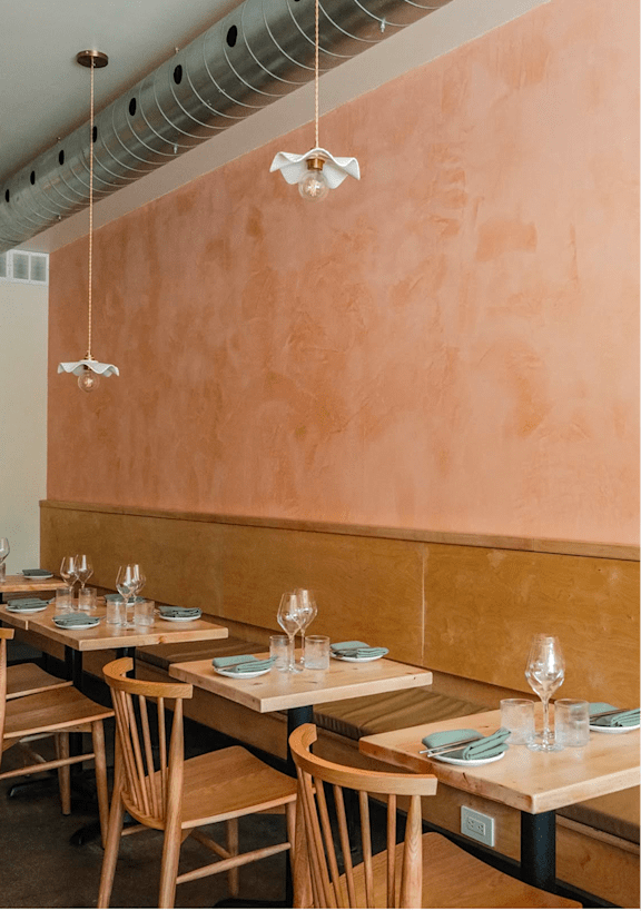 A restaurant with wooden chairs and tables set for dining.