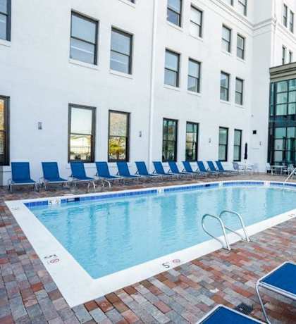a swimming pool with blue chairs in front of a building