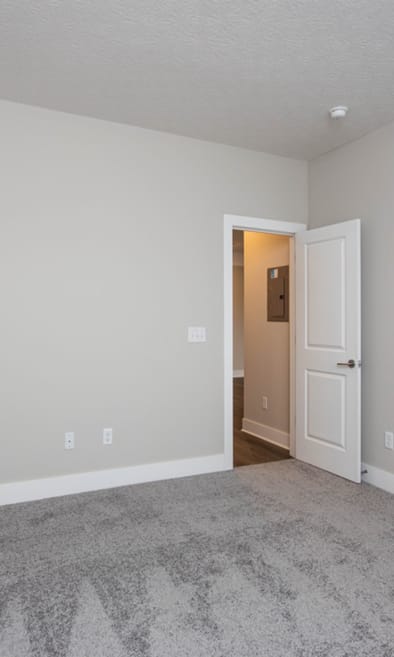 an empty bedroom with a closet and a door to a hallway