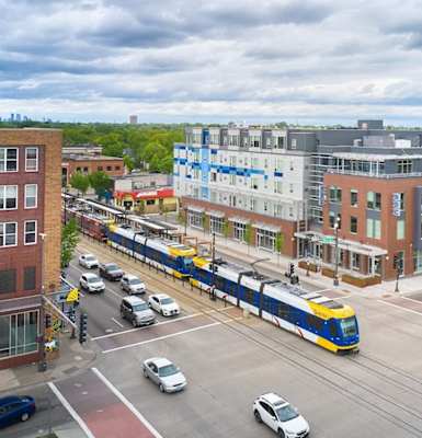 a train traveling through a city street next to a tall building