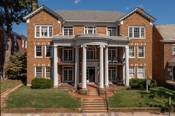 A large red brick building with a central entrance and columns.