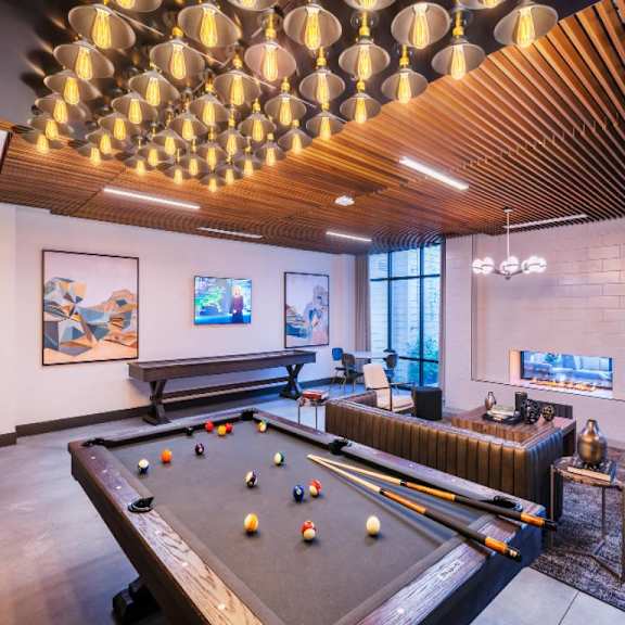 A pool table is in the middle of a room with a bench and a fireplace.