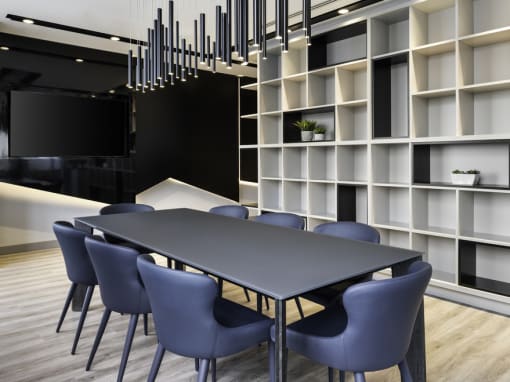 a meeting room with a large bookshelf and a black table with blue chairs