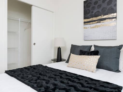 a bedroom with white walls and a white bed with black and white pillows and a black