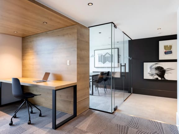 a home office with a glass walled shower and a wooden desk with a black chair