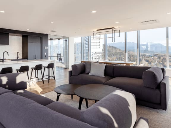 a living room with couches and a kitchen with a large window