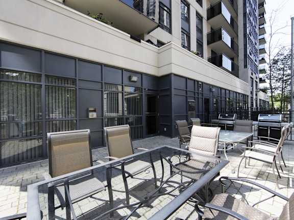 a patio with chairs and tables in front of a building