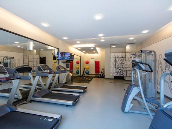 a gym with cardio equipment and a flat screen tv