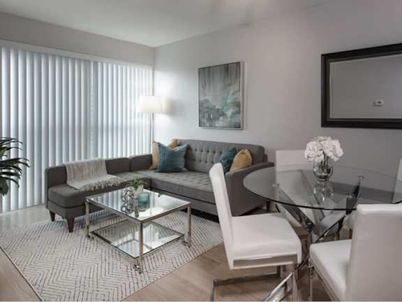 a spacious living room with a gray couch and glass coffee table in front of a large window