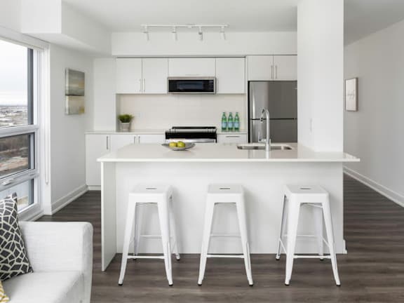 a white kitchen with white stools and a stainless steel refrigerator