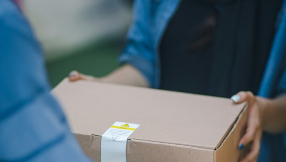 A person is holding a cardboard box with a white label on it.