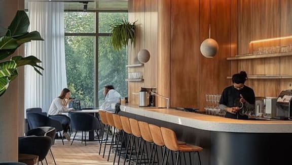 A modern cafe with people sitting and a barista working.