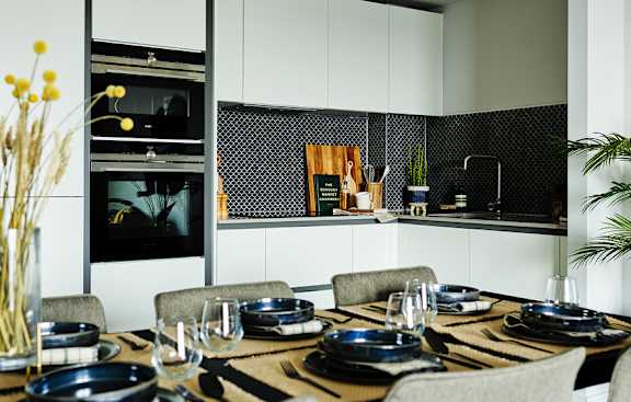A modern kitchen with a dining table set for two.