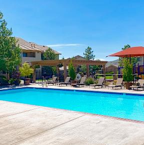 A swimming pool surrounded by a fence and chairs. at Sharlands Terrace Apartments, Apartments, Reno, NV