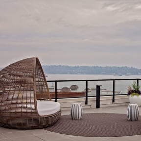 a terrace with two wicker chairs and a rug with a view of the water