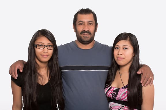 A man and two women stand together with their arms around each other.