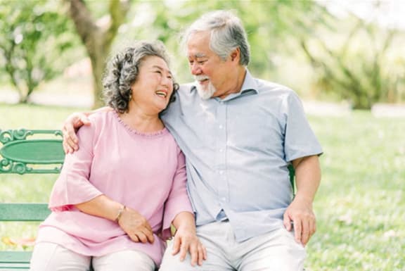 an elderly man and woman sitting on a park bench