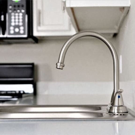 a kitchen sink with a faucet and a microwave