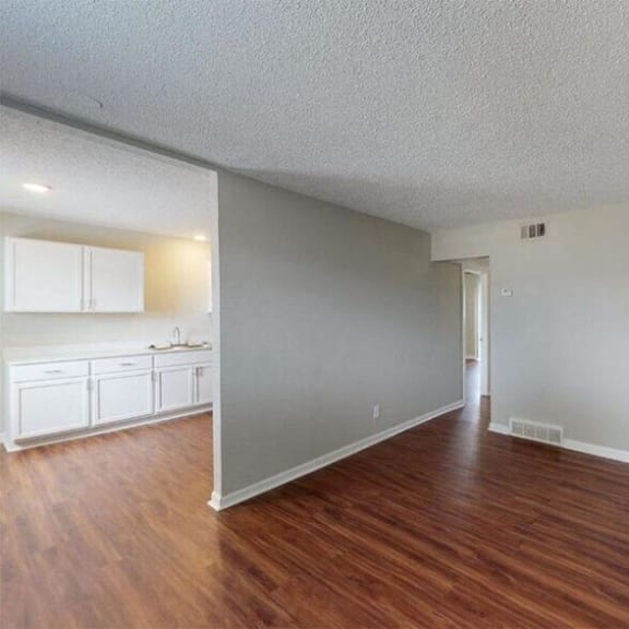 an empty living room and kitchen with wood floors