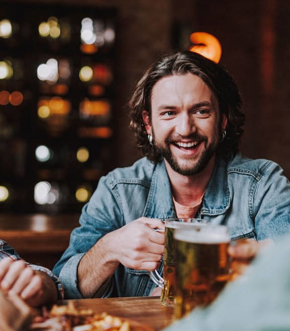 a man sitting at a table with a mug of beer