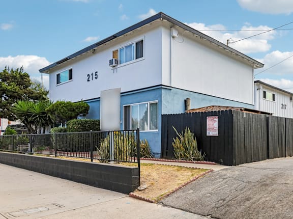 A white and blue two story house with a black fence in front.