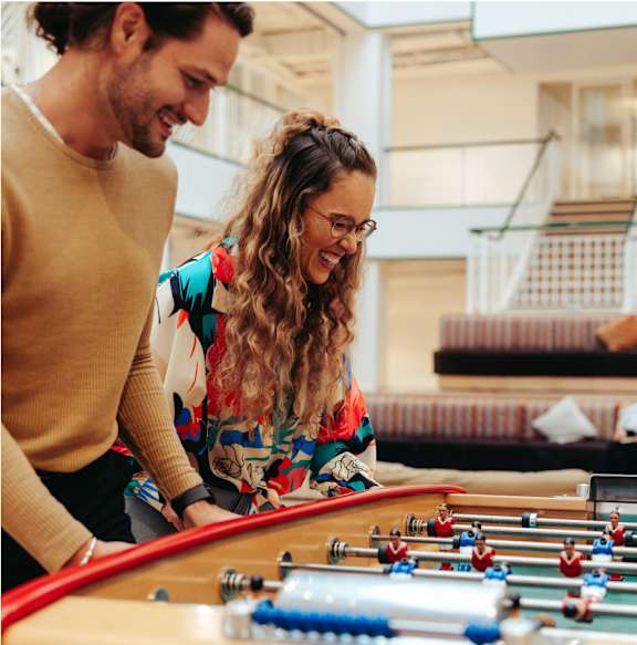 A man and a woman are playing a game of foosball together.