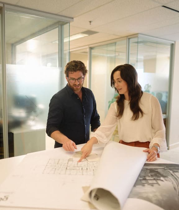 a man and a woman looking at a paper on a table