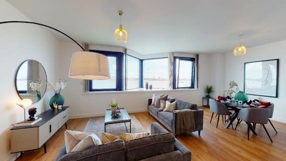 a living room and dining room with a table and chairs and a large window at The Keel Apartments, Liverpool, L3 4GE