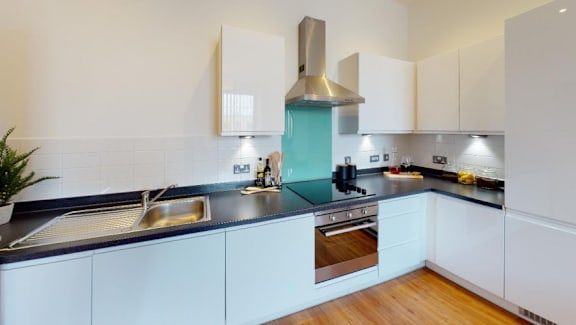 a modern kitchen with blue counter tops and white cabinets at The Keel Apartments, Liverpool, L3 4GE