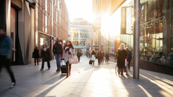 people walking down a busy city street at sunset at The Keel Apartments, Liverpool, L3 4GE