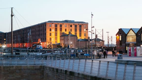 a harbor with boats and a building in the evening at The Keel Apartments, Liverpool, L3 4GE