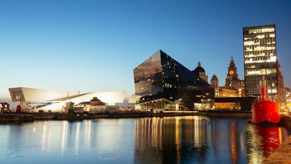 a view of the city from the water at night at The Keel Apartments, Liverpool, L3 4GE