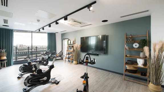 a gym with exercise bikes and a tv on the wall at Vox Apartments, Manchester, M15 4YD