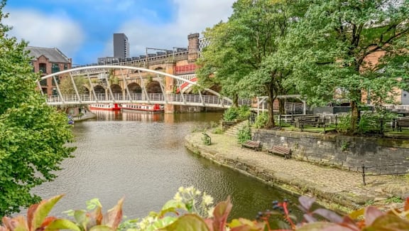 a bridge over a river in a city with trees at Vox Apartments, Manchester
