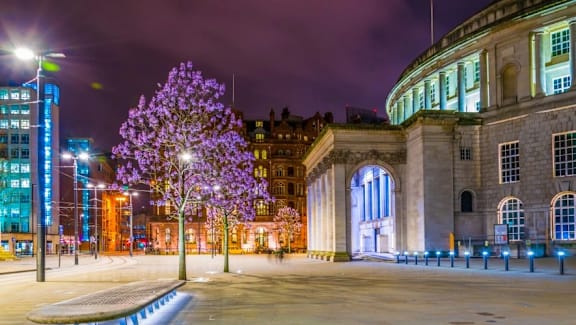 a city at night with a purple tree and buildings at Vox Apartments, Manchester