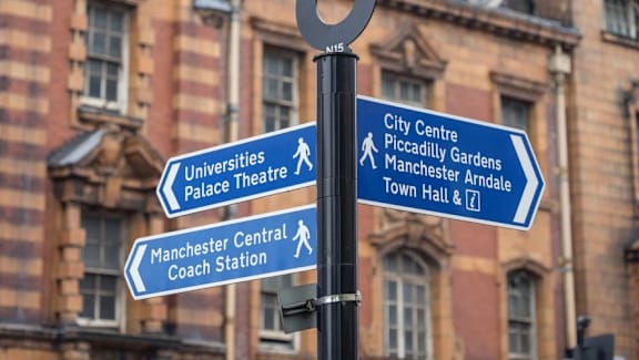 a pole with street signs on it in front of a building at Vox Apartments, Manchester