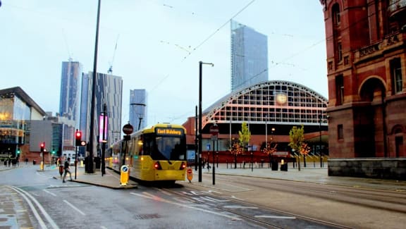 a yellow bus driving down a street in a city at Vox Apartments, Manchester