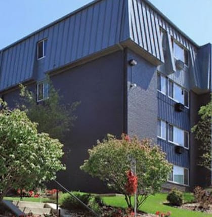 A modern building with a blue exterior and a landscaped area in front.