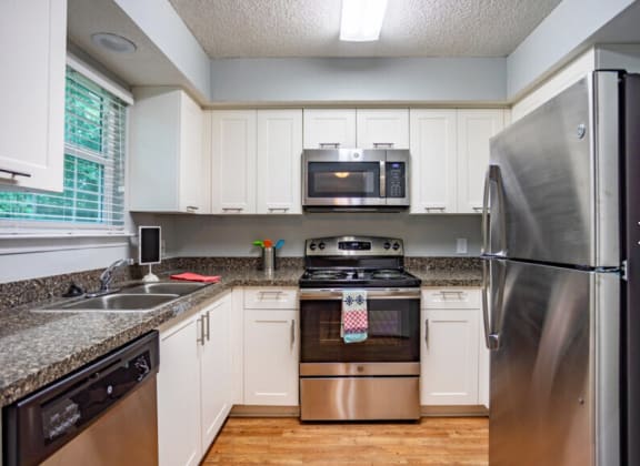 Kitchen with Wood-style Flooring and Stainless Steel Appliances at MIrabelle Apartments in Mobile, AL