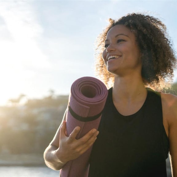 a woman holding a rolled up yoga mat