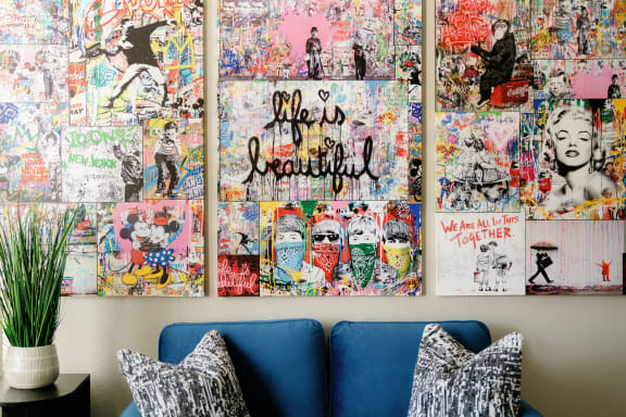 A wall covered in graffiti art with a blue couch in front of it. at The Vine on 8th, Las Vegas, NV, 89101