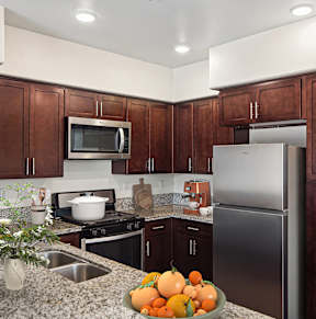 A kitchen with brown cabinets and a silver refrigerator.