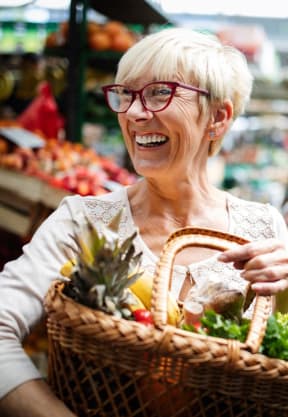 a woman holding a basket of vegetables in a market at Great Hills, Austin, TX