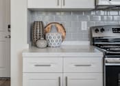 Thumbnail 13 of 21 - Kitchen with white cabinets and a black stove at 200 City View, Provo